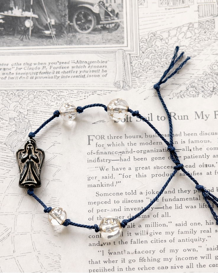 Anther House Navy blue beaded bracelet with a silver angel charm on an old book page background Handmade in Philadelphia