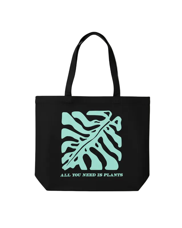 Black tote bag with teal leaf design and text 'All You Need Is Plants' on a white background