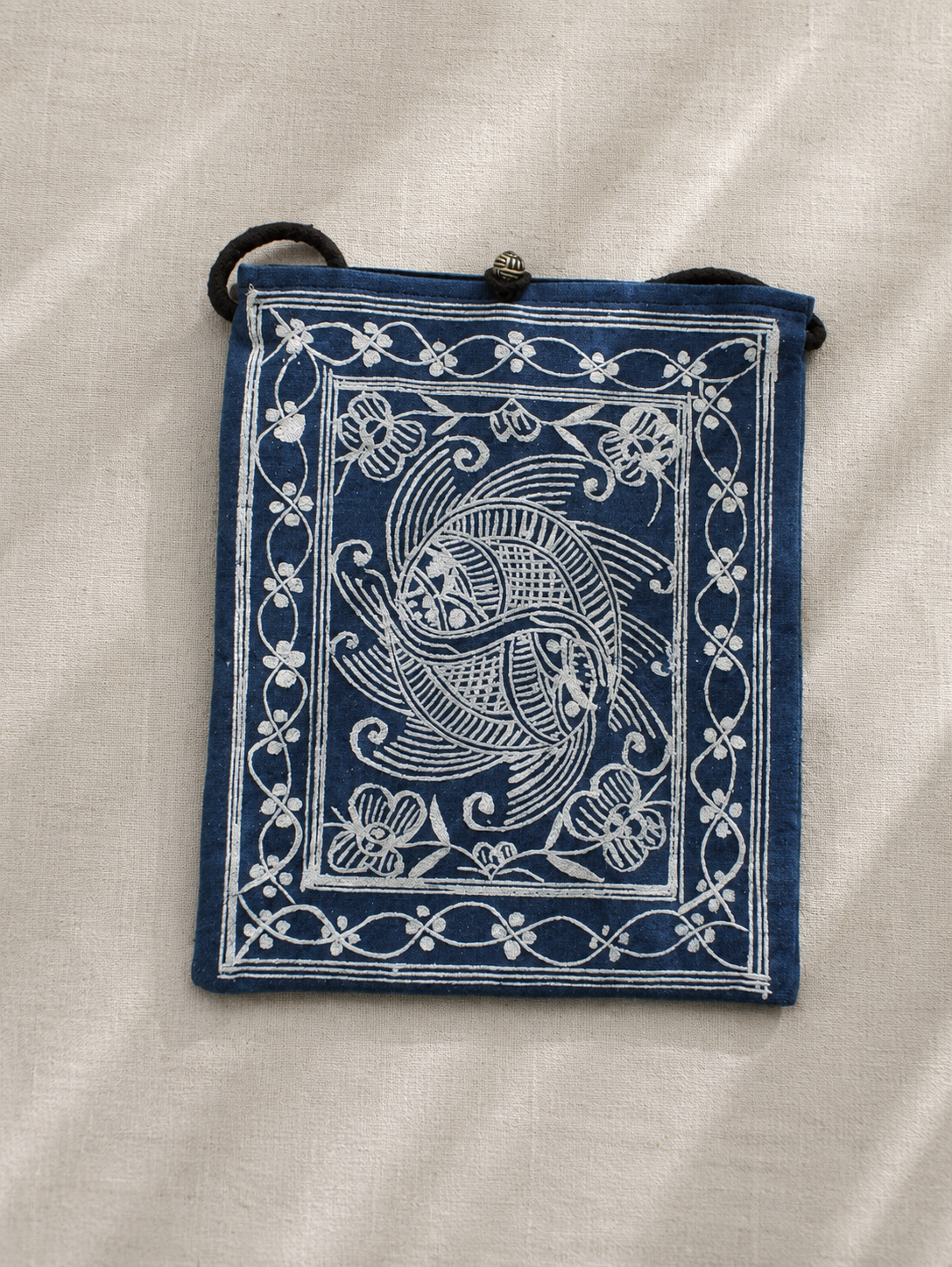 Indigo dyed artisan textile pouch featuring Chinese heritage inspired patterns, woven details, and vintage style closure