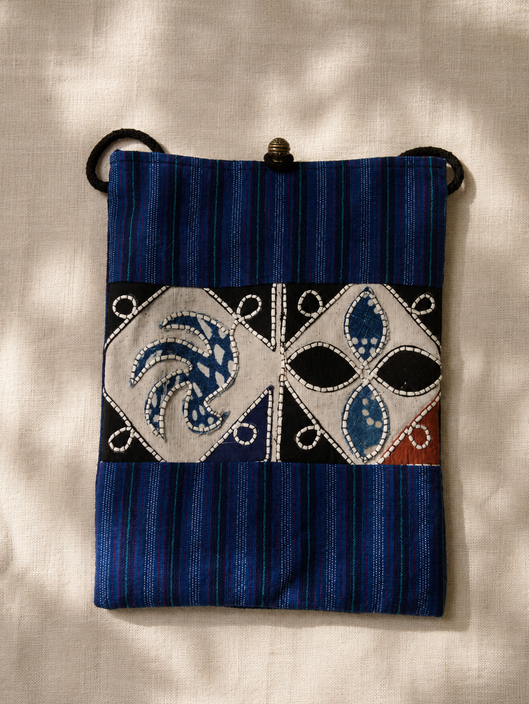 Indigo dyed artisan textile pouch featuring Chinese heritage inspired patterns, woven details, and vintage style closure