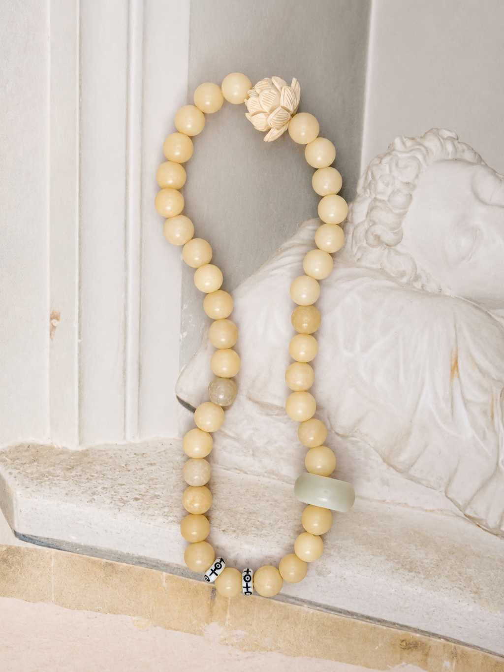 Handmade natural stone beaded bracelet with neutral cream beads, carved lotus charm, and minimalist artisan design