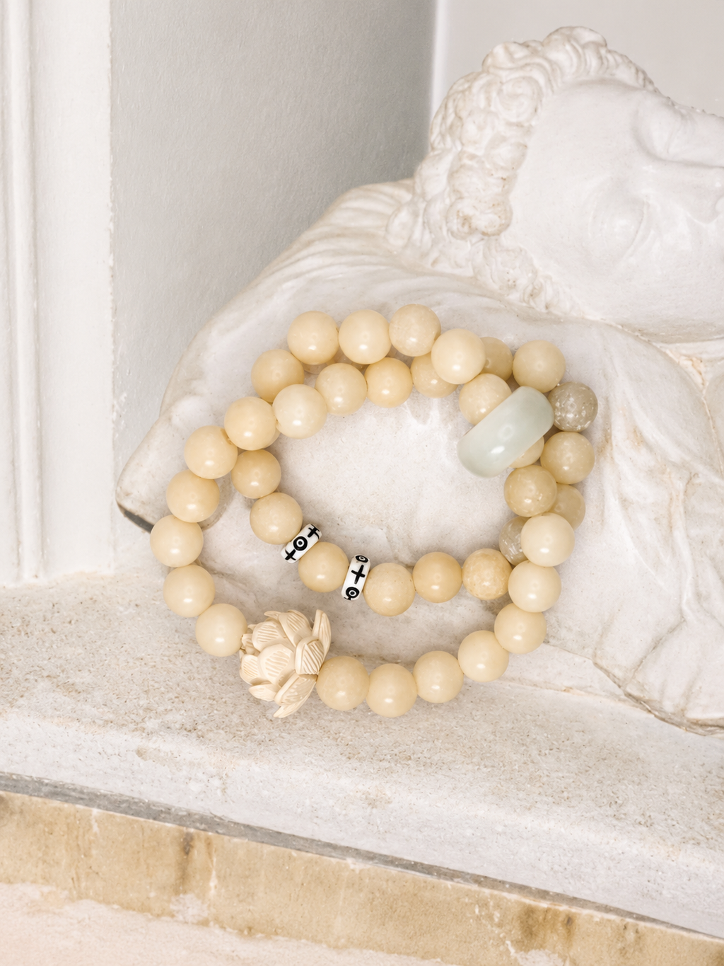 Handmade natural stone beaded bracelet with neutral cream beads, carved lotus charm, and minimalist artisan design